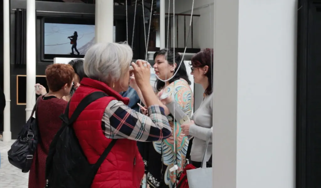 Visitantes olham pelos monóculos da exposição