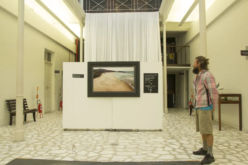 Visitante observa fotografia de land art na exposição