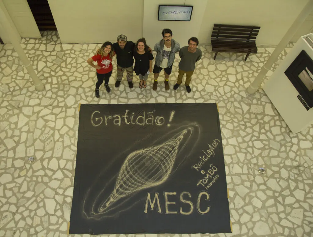Equipe ao redor de uma mandala de agradecimento desenhada no chão do museu